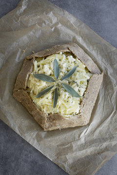 Pie dough and ingredients for a potato galette. Photographed on a greay background from top view.