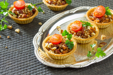 Holiday appetizer: tartlet with beans, meat and walnuts on a fes