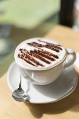 Hot cocoa in a white cup In a cafe on the table by the window