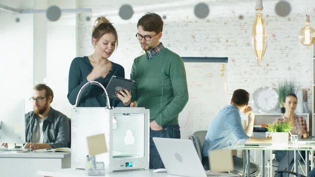 Beautiful Creative Girl Shows Tablet Computer To Her Stylish Male Colleague. They Locate in a Busy Creative Loft Office with Young People Working in Background.  Shot on RED EPIC (uhd). 