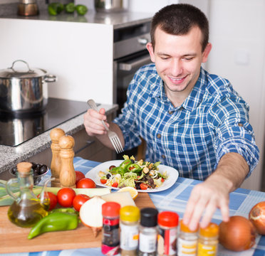 man preparing salad in kitchen at home