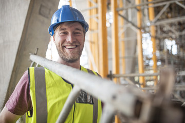 Construction worker on construction site carrying ladder