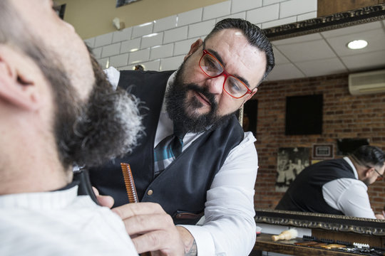 Barber cutting man's beard