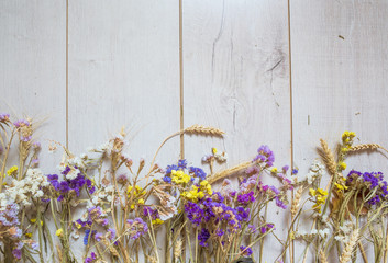 Autumnal bouquet of flowers and wheat ears on wooden rustic table background. Flat lay, top view.