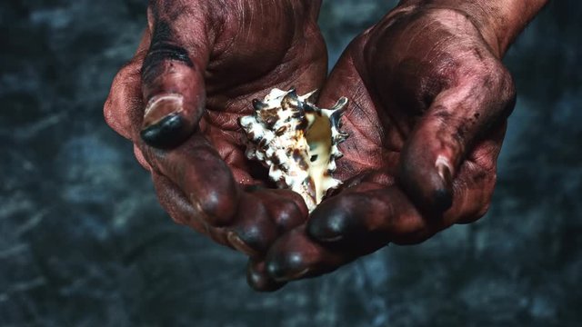 4k Technical Composition of Dirty Mechanic Hands Holding Seashell