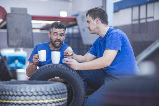 Two mechanics on a coffee break in workshop