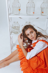 Woman sitting on floor and holding jar with gold fish