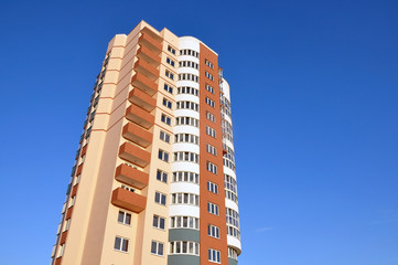 A modern multistory apartment house with round balconies against the blue sky. Lookup. Place for text.
