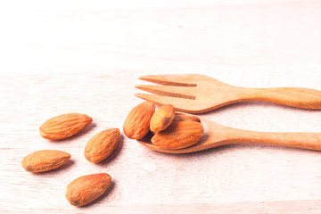 Almonds pour from wood spoon on wooden table