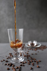 hot coffee in the tall glass with coffee beans on the grey stone table.