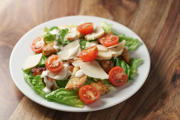 caesar salad with cherry tomatoes on wooden table