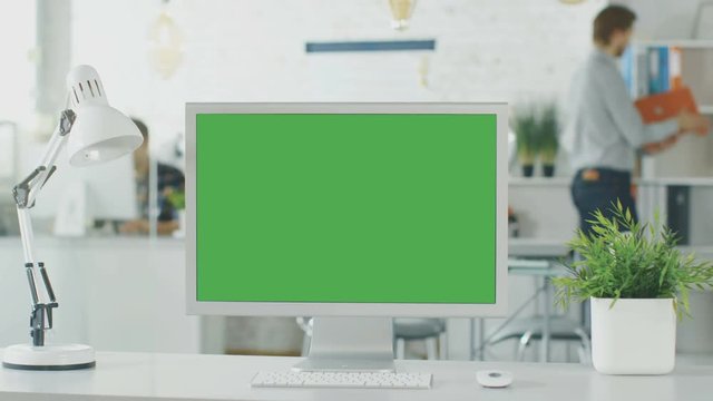 Close-up of a Green Screen on a Personal Computer. In Background Bright Office where People go Through Office Routine. Shot on RED EPIC (uhd).