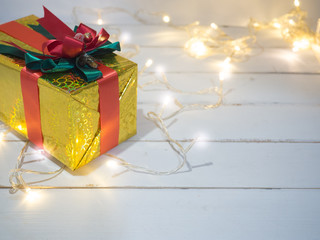 Gold box with red ribbon and decoration golden object white background  on wooden table for Christmas and The New Year .