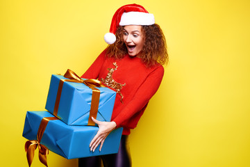 Young girl in a red sweater and hat holding gifts and rejoices