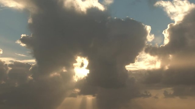 Cloudscape time lapse with sun beaming through large clouds as they pass the sky.
