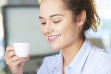 Coffee break in the office. Close-up shot of young assistant drinking a cup of coffee while sitting in the office.