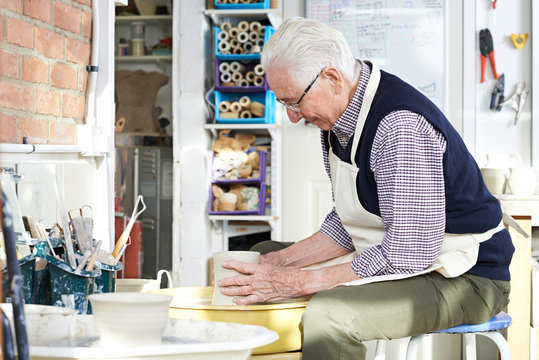 Senior Man Working At Pottery Wheel In Studio