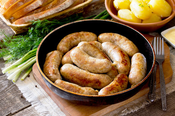 Homemade meat raw sausage on a cast iron frying pan, vegetables,