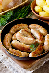 Homemade meat raw sausage on a cast iron frying pan, vegetables,