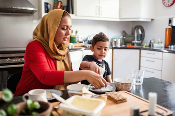 Mother and son having breakfast at dining table in kitchen