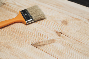 Brushed wooden surface with a brush lying on the background. The concept of decorating repairs