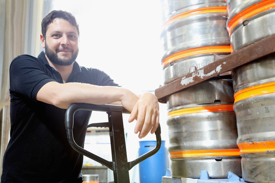 Portrait of worker in brewery organising beer barrels for delivery