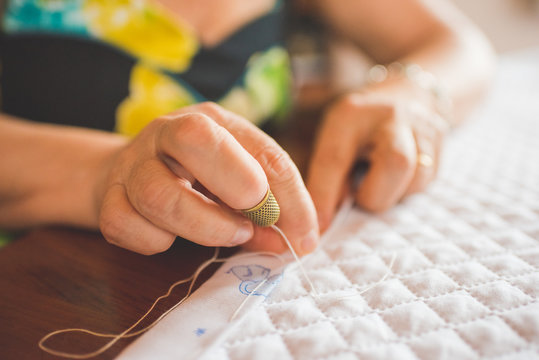 Cropped view of woman sewing hem on quilt