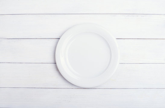 Single empty plate on white wooden background. Top view with copy space. High key