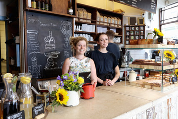 Colleagues at counter in coffee shop looking at camera smiling
