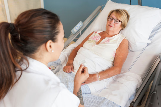 Nurse tending to patient in hospital bed