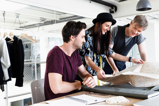 Colleagues at desk looking at folding map smiling