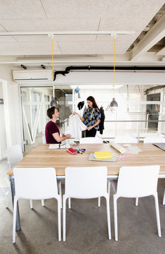 Fashion designer showing colleague complete garment