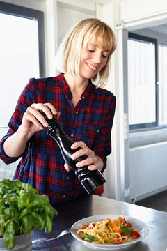 Woman seasoning bowl of pasta
