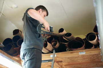 Male worker in leather workshop, measuring thickness of leather, low angle view