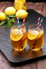 Iced tea with lemon slices, mint and ice on rustic background