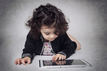 fillette deux ans cheveux bruns utilisant une tablette