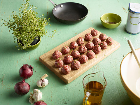 Rows of raw prepared greek meatballs on chopping board