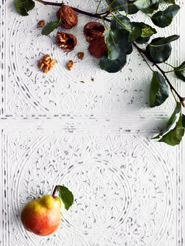 Pear and branch beside walnuts
