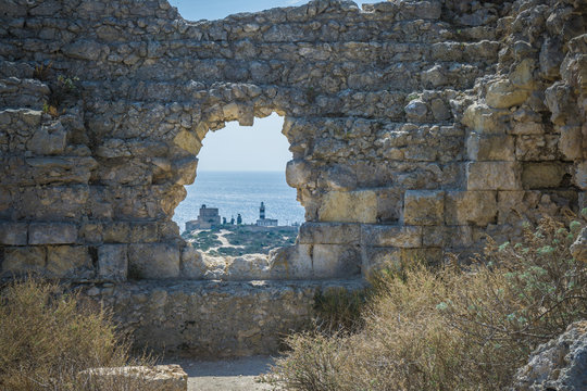 View of lighthouse through hole in stone wall, Cagliari, Masua, Sardinia, Italy