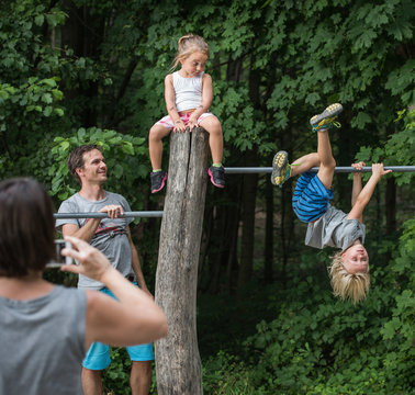Mother photographing children playing on monkey bar