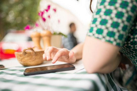 Cropped view of woman at pavement cafe using smartphone