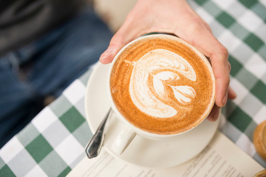 Cropped view of man's hand holding coffee cup