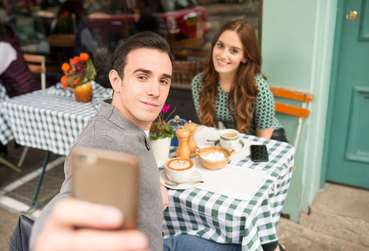 Couple at pavement cafe talking selfie