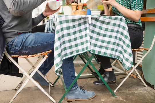 Low section of couple at pavement cafe table