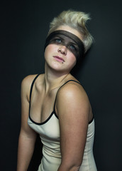 portrait of blonde girl in a beige dress transparent black blindfold looking up