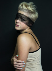 Naklejka premium portrait of blonde girl in a beige dress transparent black blindfold looking up