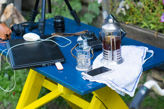Camera equipment, laptop and cafetiere on table in garden