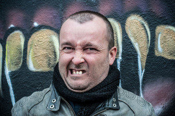 homme agressif en extérieur devant un mur de graffiti