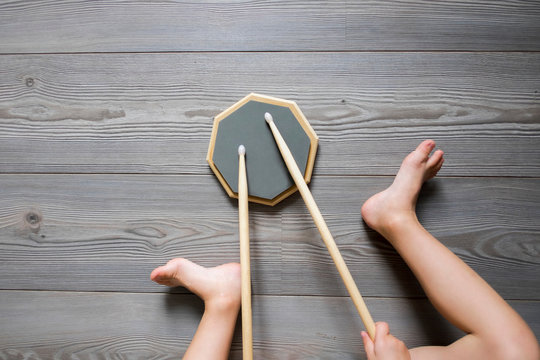Overhead cropped view of boy sitting on wooden floor drumming