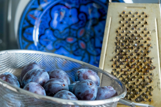 Plums in sieve and grater